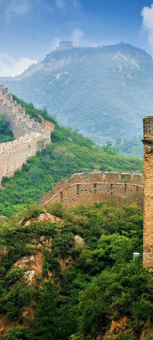 万里长城蜿蜒于苍翠群山之间，上方是澄澈蓝天，景致壮阔清新。