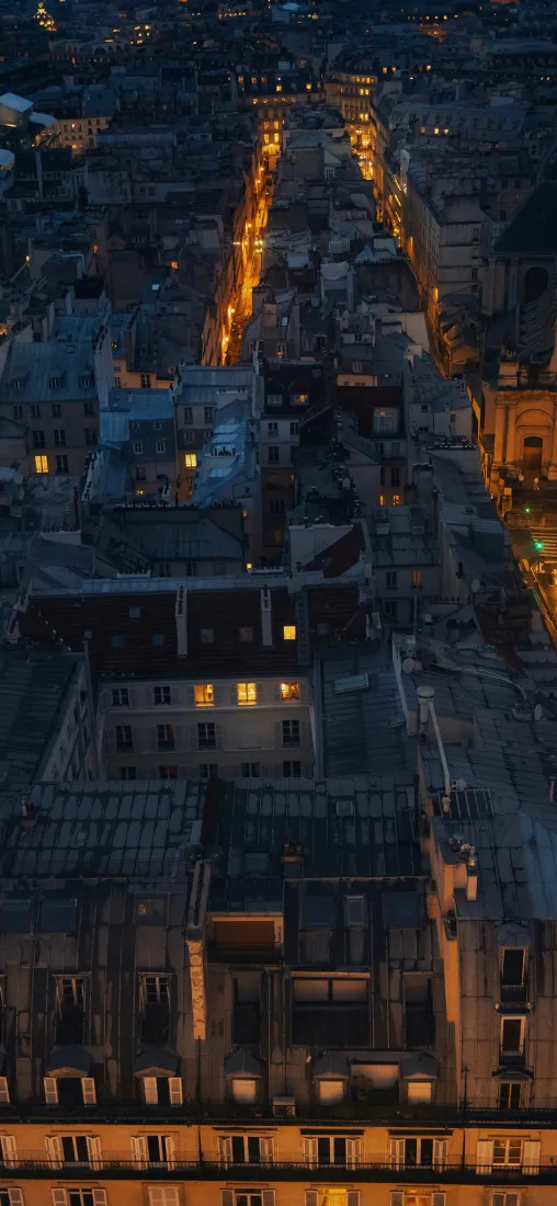 高空俯瞰的城市夜景，暖黄色街灯与建筑灯光在暗调中延伸。