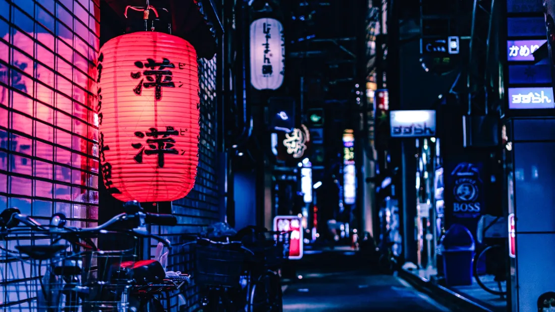夜晚日式小巷，左侧悬挂红色灯笼，两侧霓虹日文标牌，巷道向远处延伸。