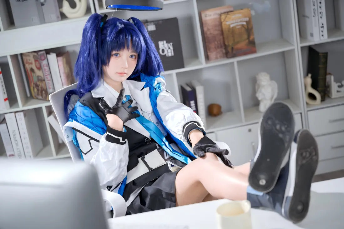 蓝发双马尾coser身着蓝白制服，坐于书架前的椅子上，双脚搭在桌面