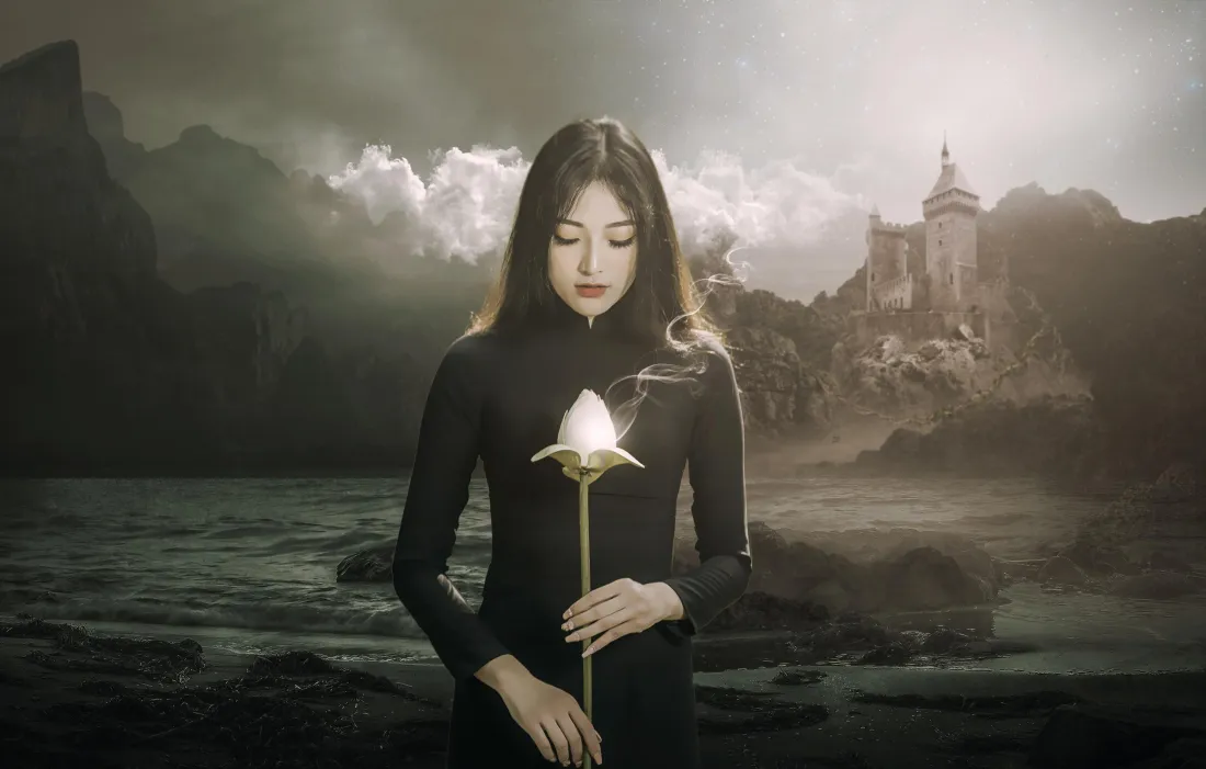 3k黑衣少女壁纸|城堡背景图片 - 暗黑梦幻场景「哲风壁纸」 黑衣长发女子手持发光白花,立于湖畔礁石,背景为阴天山脉与远处城堡。