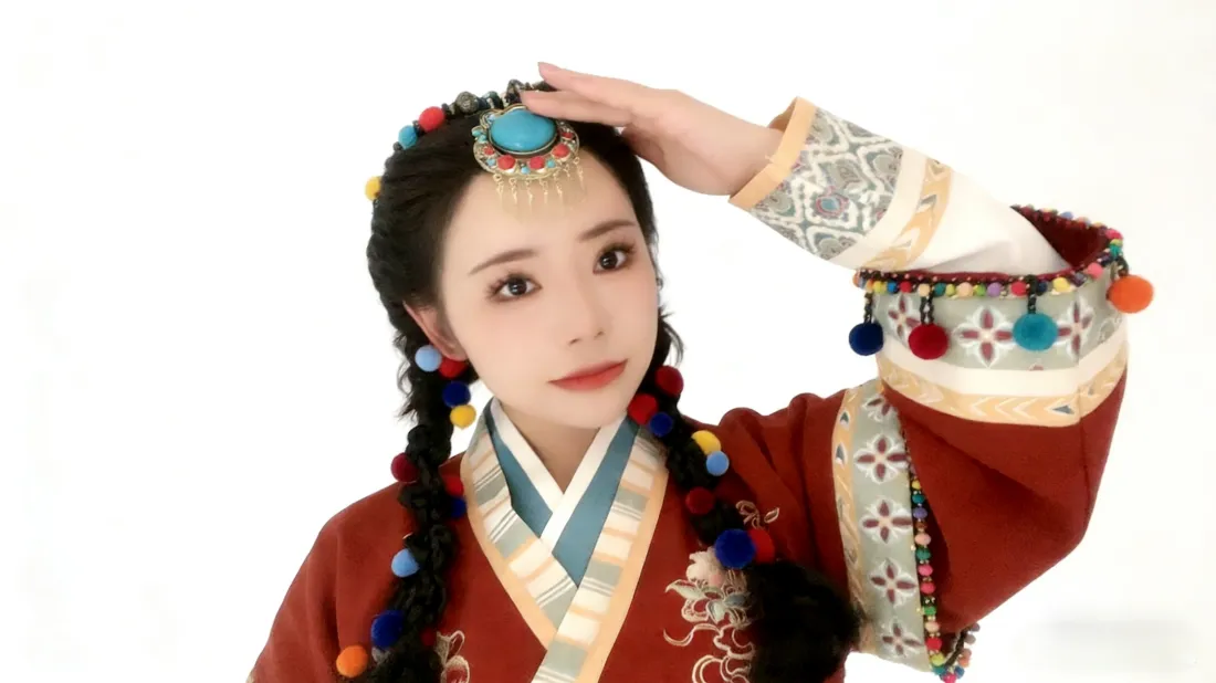 纯白背景下身着红色藏族服饰、佩戴彩珠头饰的编发少女抬手扶额