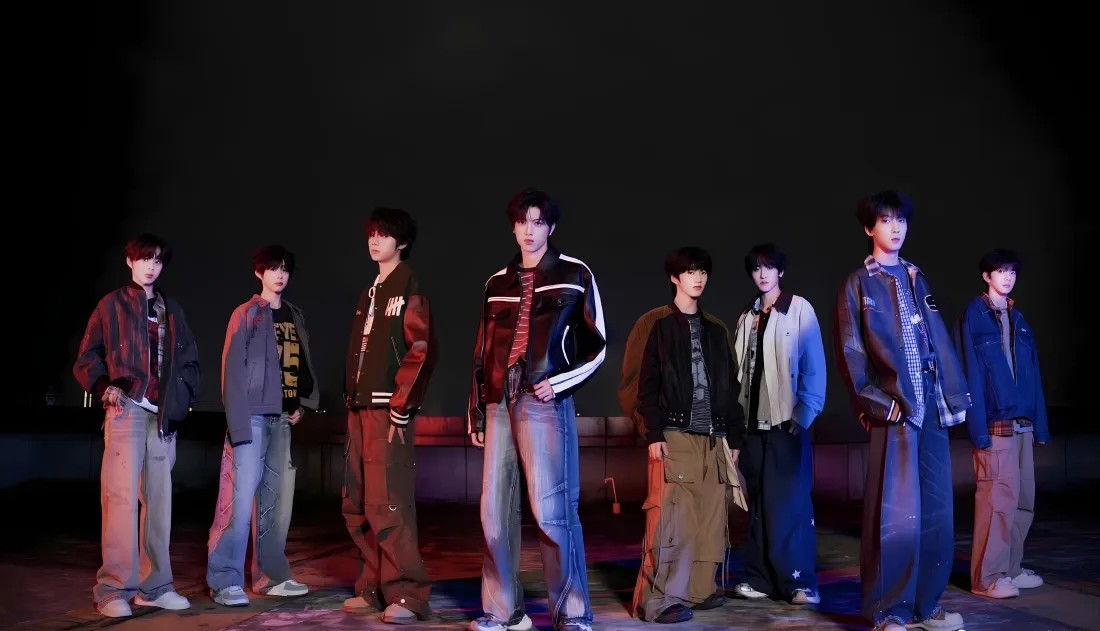 TF家族8位少年身着休闲夹克牛仔裤，在暗调红蓝舞台灯光下并排站立
