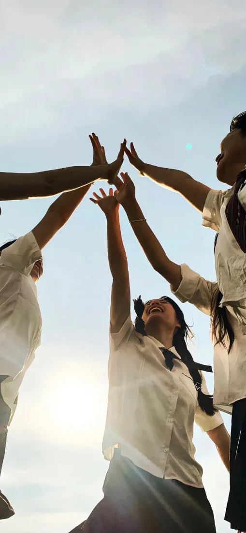 低角度仰拍多名穿JK制服的少女在蓝天阳光下伸手击掌