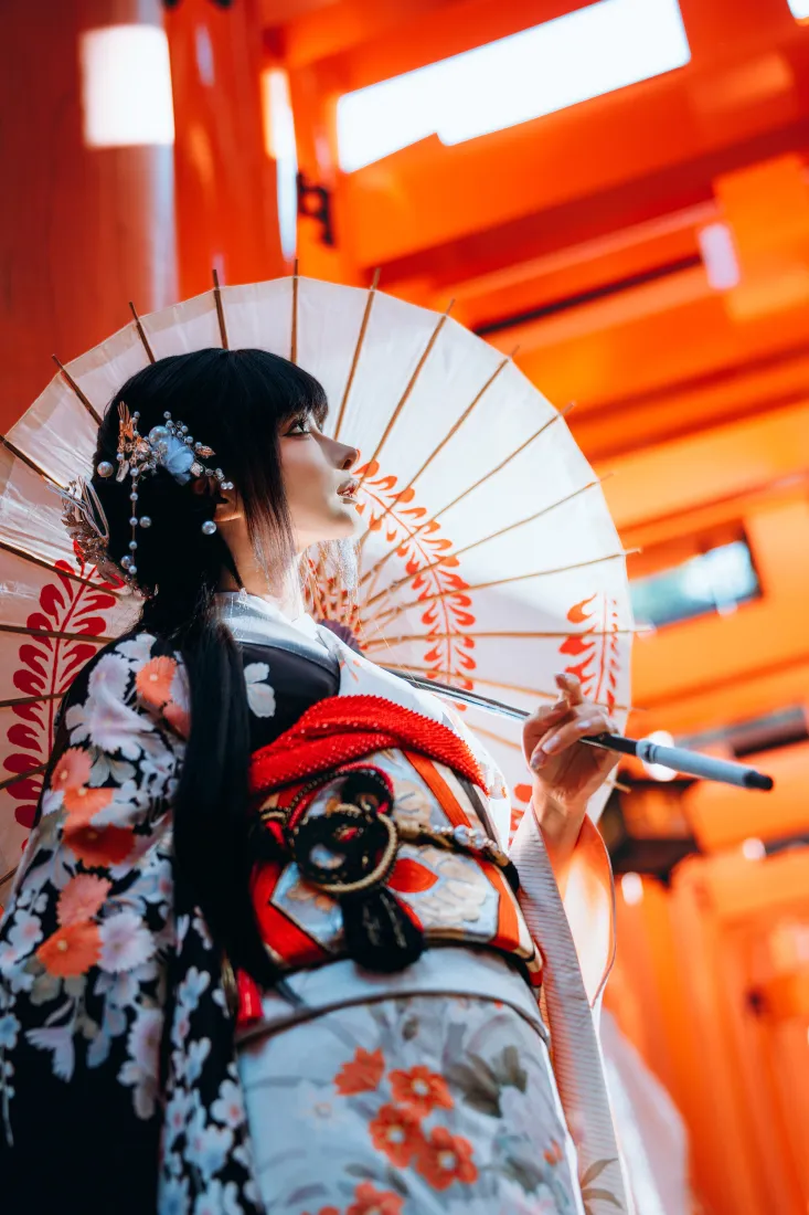 身着印花和服的黑发少女手持油纸伞，立于橙红色鸟居前，侧头仰望。