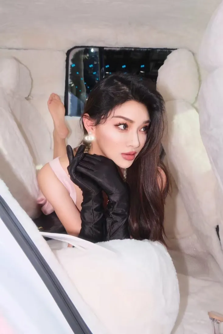 长发美女戴黑色长手套，在米白内饰的车内摆拍，窗外是夜景