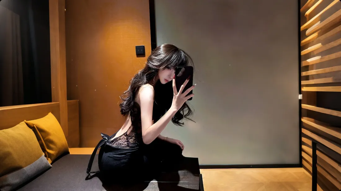 长发美女在暖调居家室内对镜自拍，身着黑色露背蕾丝服饰