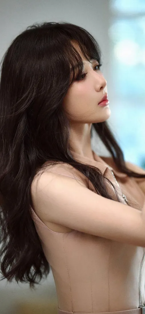 室内窗边，黑发长卷发美女侧身抬臂，望向画面右侧，背景虚化。