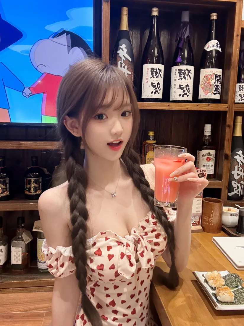双麻花辫女生穿爱心印花露肩装，在居酒屋手持西柚饮品。