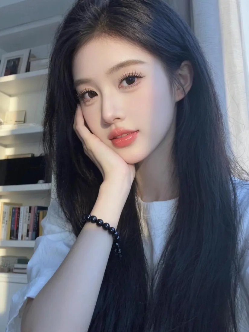 室内窗边，黑长直长发女生手托脸颊，穿白上衣，背景为虚化书架