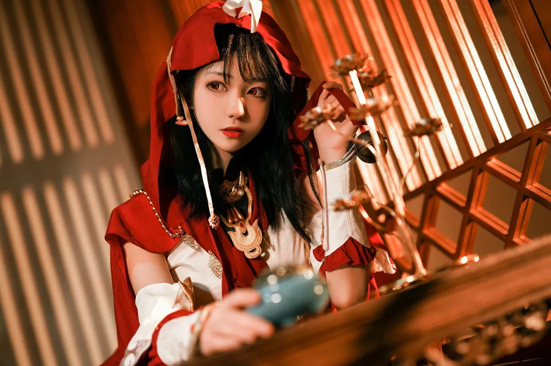 3k剑网3喵萝cos壁纸|古风室内暖光背景图片 - 南桃Momoko「哲风壁纸」 暖光古风室内,红衣coser手持青瓷杯,背景为木质格栅。