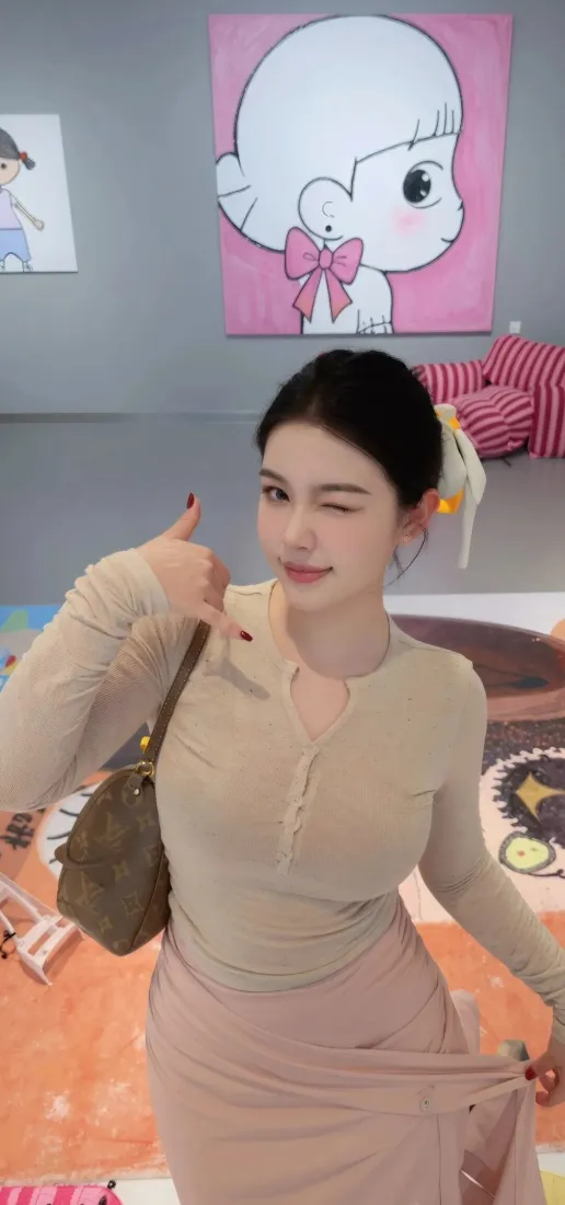 室内年轻女子wink竖拇指，穿卡其色修身裙，挎棕色包，背景有卡通挂画
