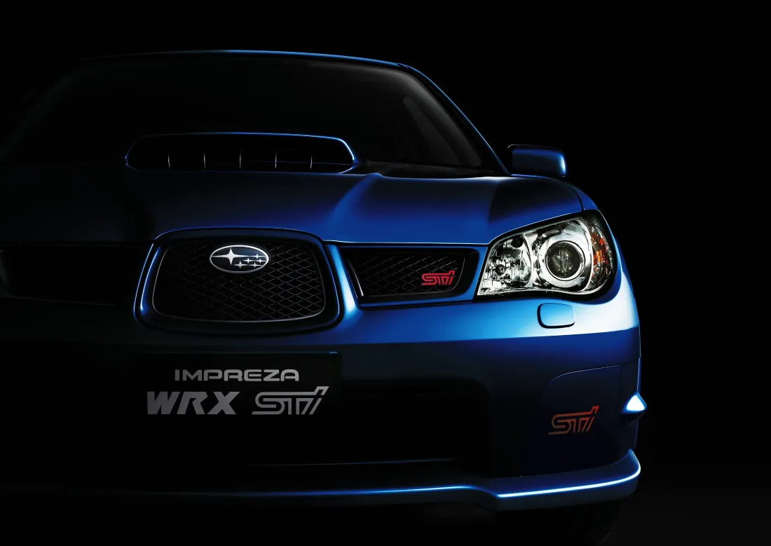 纯黑背景下的蓝色斯巴鲁翼豹WRX STI前脸特写，光影勾勒车身轮廓