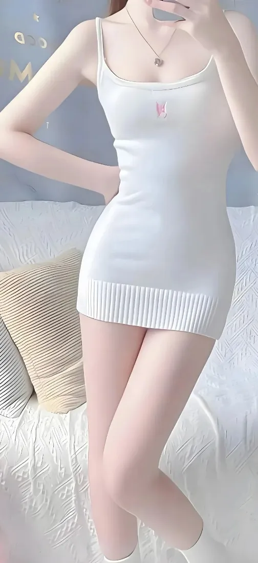 穿白色吊带针织短裙的女性居家自拍，背景为白色沙发与浅灰墙面