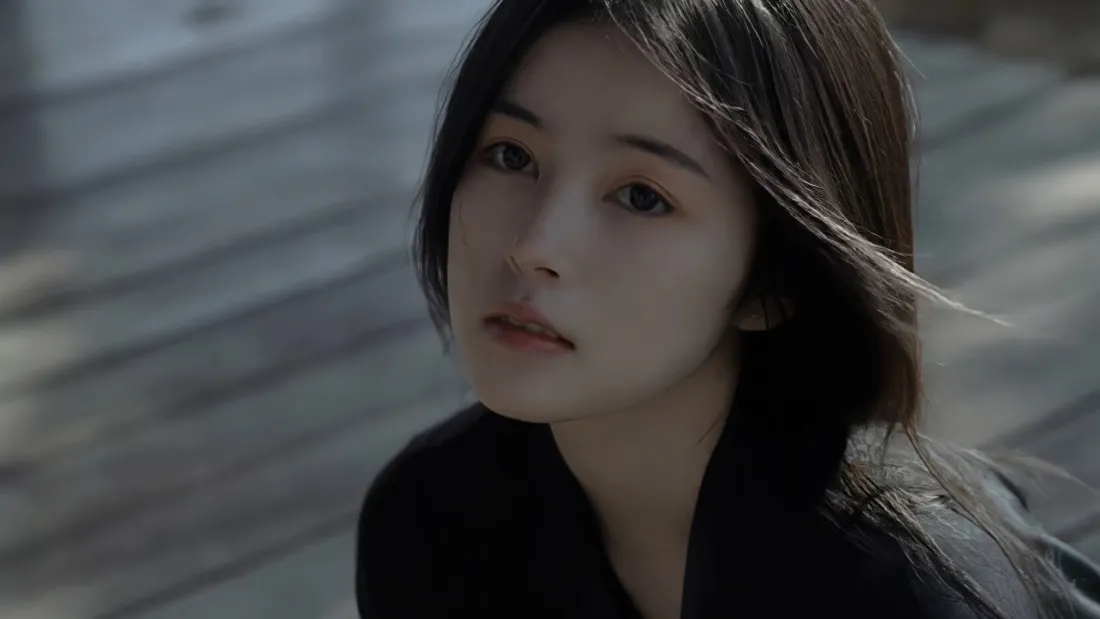 户外石阶旁的清冷短发黑衣美女，神情淡然，背景虚化。