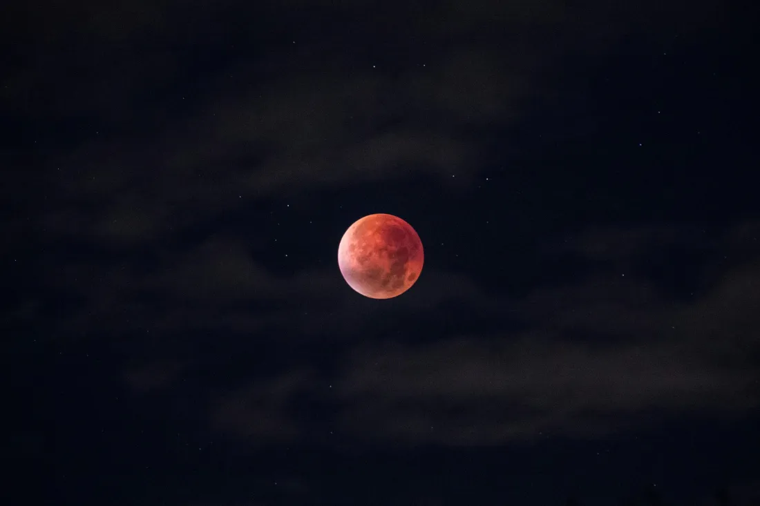 黑夜暗云笼罩的夜空里，一轮血红色的红月亮悬于画面中央，点缀零星星点