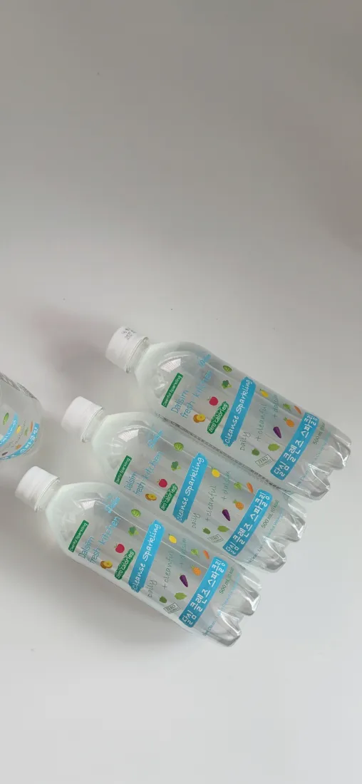 浅白背景上斜放着几瓶带彩色颗粒的透明塑料水瓶