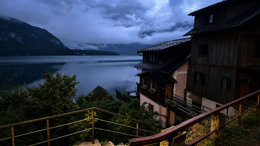 黄昏湖畔小镇，木栏杆旁临湖木屋，远山云雾笼罩，湖面静谧。