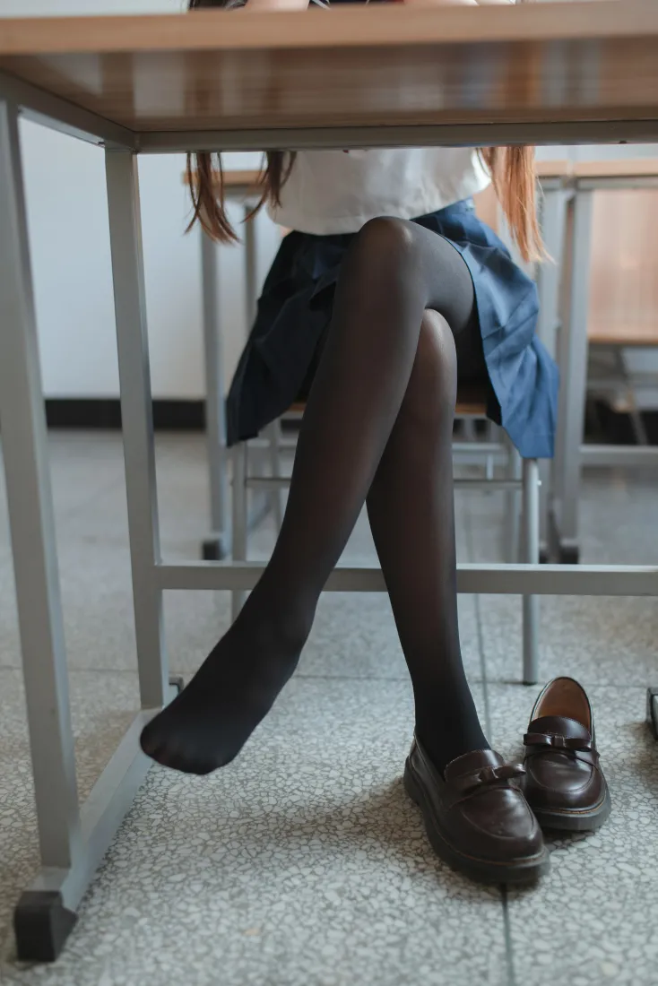 教室课桌下，穿黑丝水手服的少女翘腿而坐，脚边放着乐福鞋。