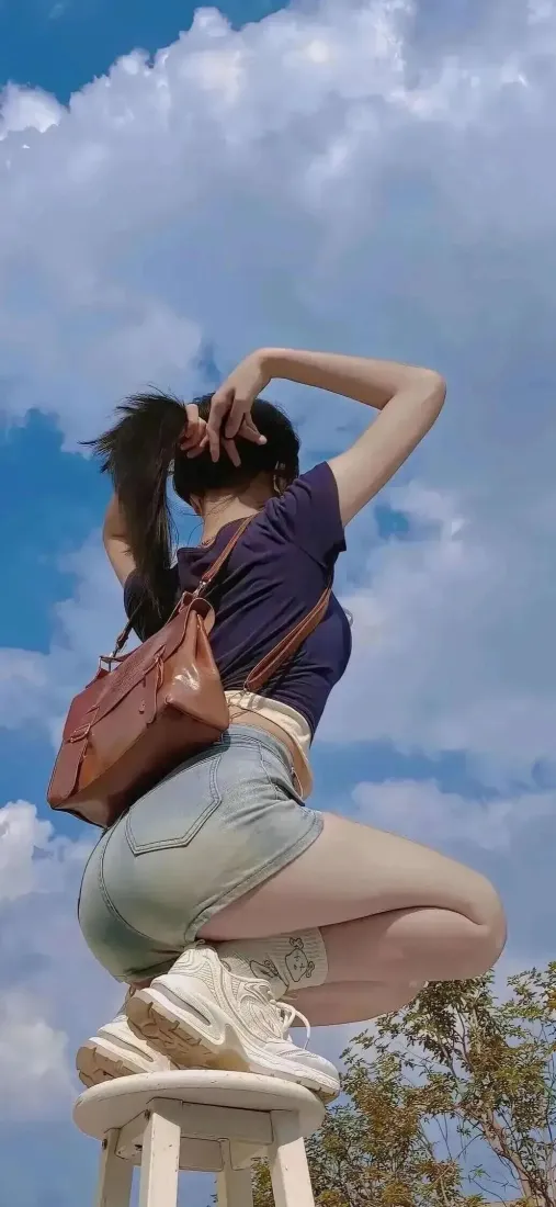 户外美女手机壁纸｜蓝天背景图片 - 牛仔短裤蹲姿少女「哲风壁纸」