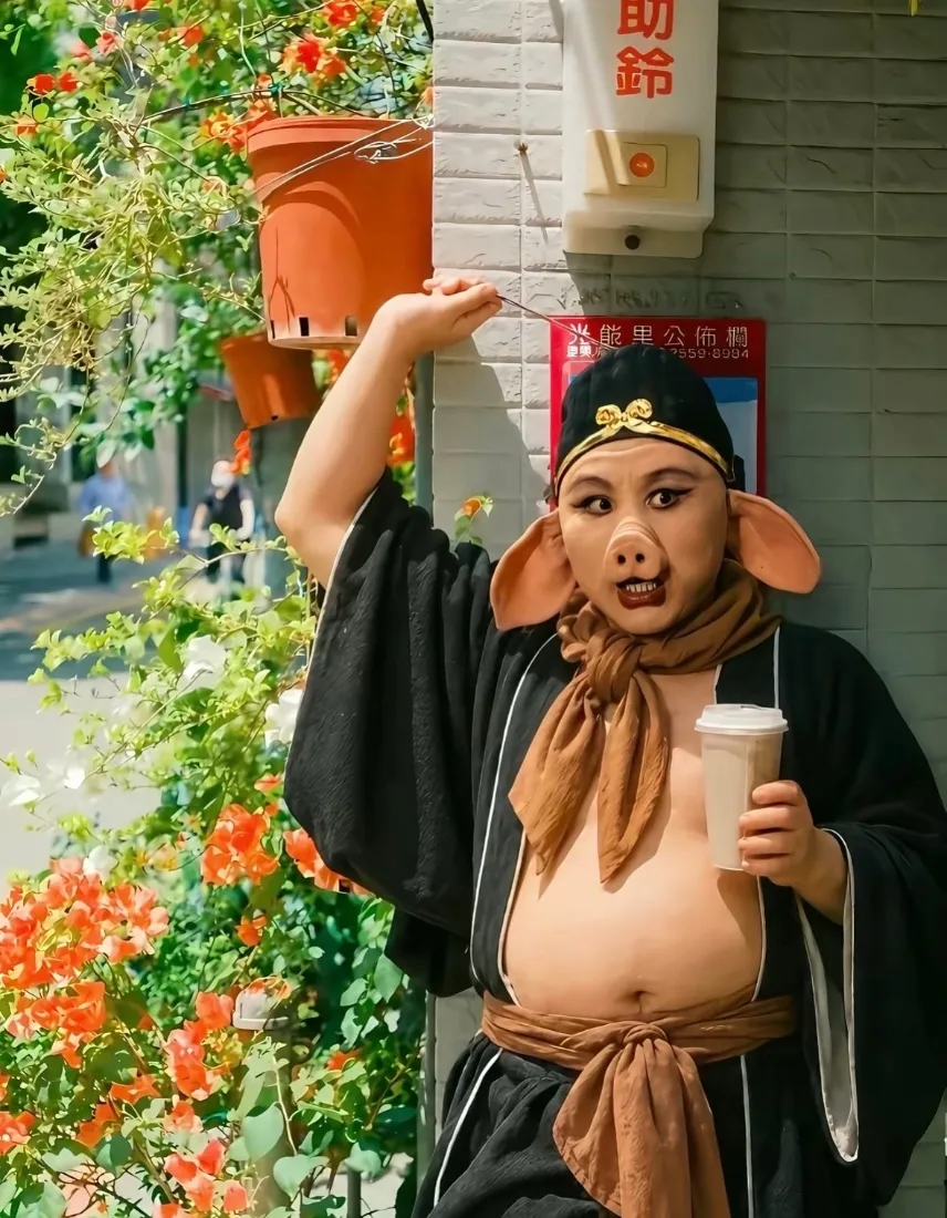 街边花墙旁，猪八戒coser手持奶茶，造型趣味搞怪