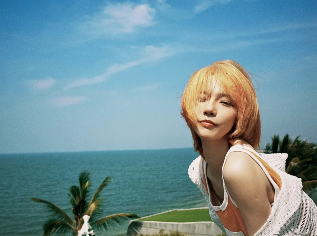 橘色短发女子在海边，背景是蓝天碧海与椰树，夏日度假氛围。