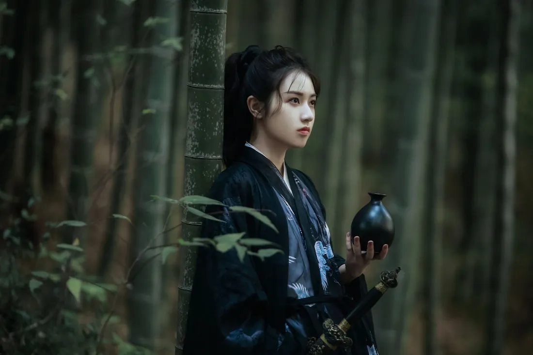 竹林中黑衣古装侠女倚竹而立，手持黑酒壶，身侧佩剑，气质清冷。