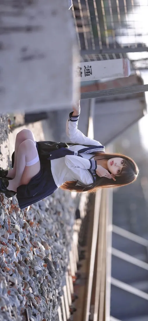 春日户外站台，穿水手服白丝的JK少女蹲在碎石地面上。