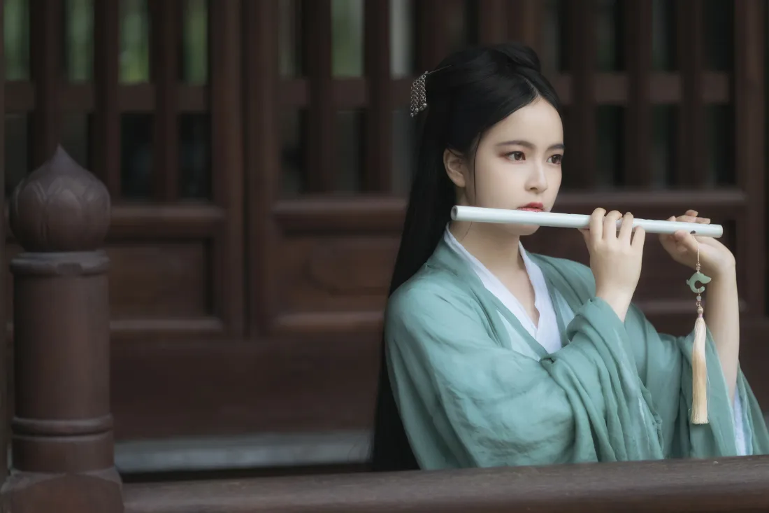 4k古风绿衣女子壁纸|木廊吹笛背景图片 - 江湖思愁意境「哲风壁纸」 身着青绿色汉服的女子在古建木廊下吹奏玉笛,神情清冷