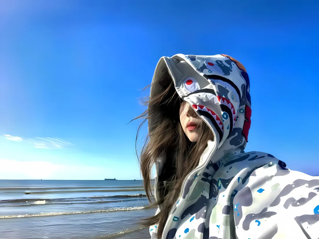 3k海边美女壁纸|蓝天背景图片 - 鲨鱼连帽外套自拍「哲风壁纸」 海边晴天,长发女生穿鲨鱼连帽外套自拍,背景是蓝天与海浪。