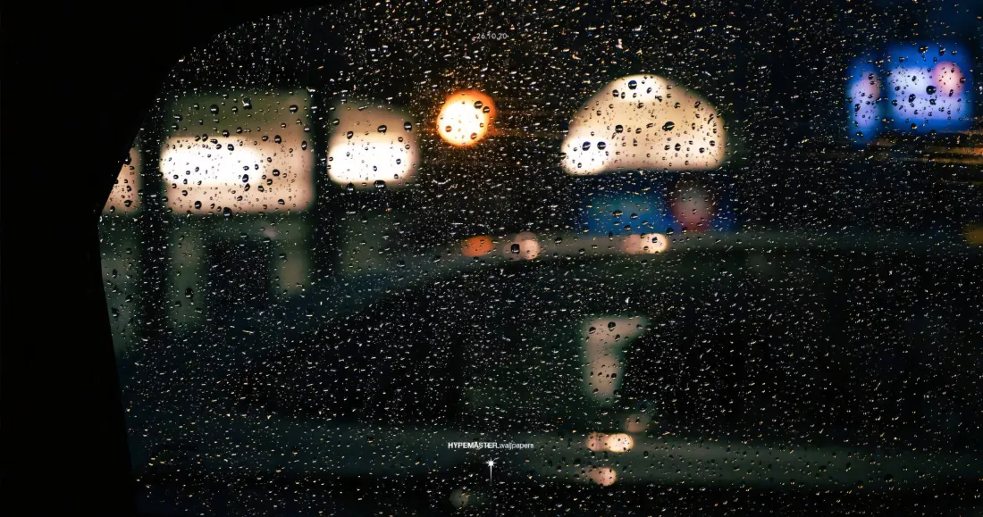 布满雨滴的车窗玻璃外，虚化的城市夜景灯光朦胧晕开。