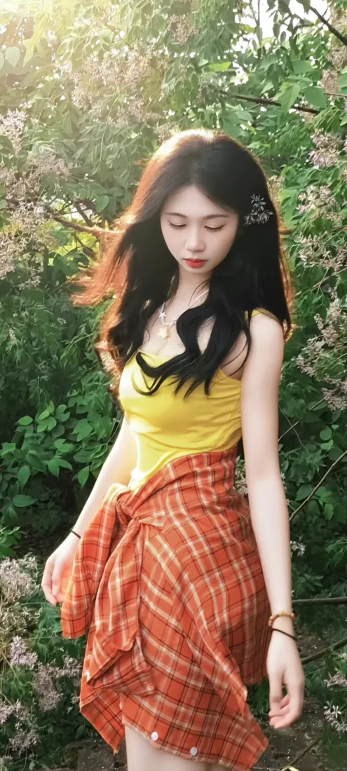 林间绿植花丛中，穿黄色吊带、系橙红格纹裙的黑长卷发少女垂眸站立。