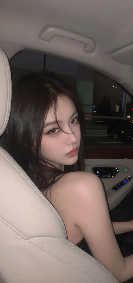 夜晚车内，长发露肩年轻女生回头看向镜头，暗调氛围。