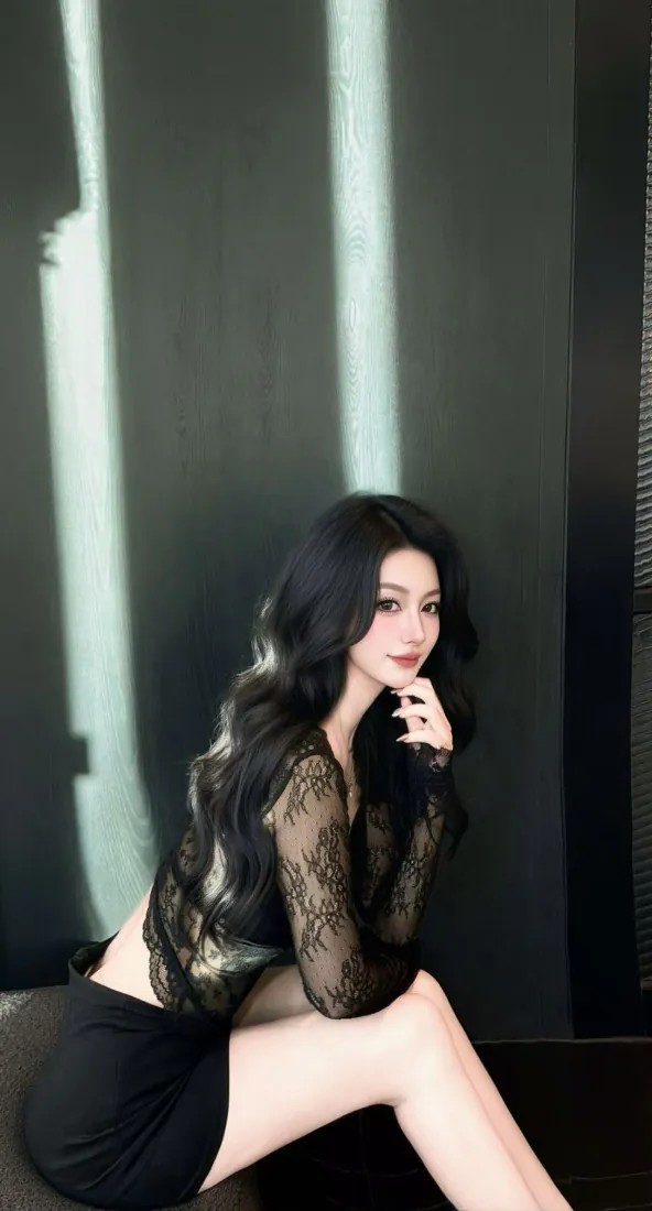 暗调室内，长卷发女子穿黑色蕾丝上衣与短裙，坐姿托腮看向镜头。