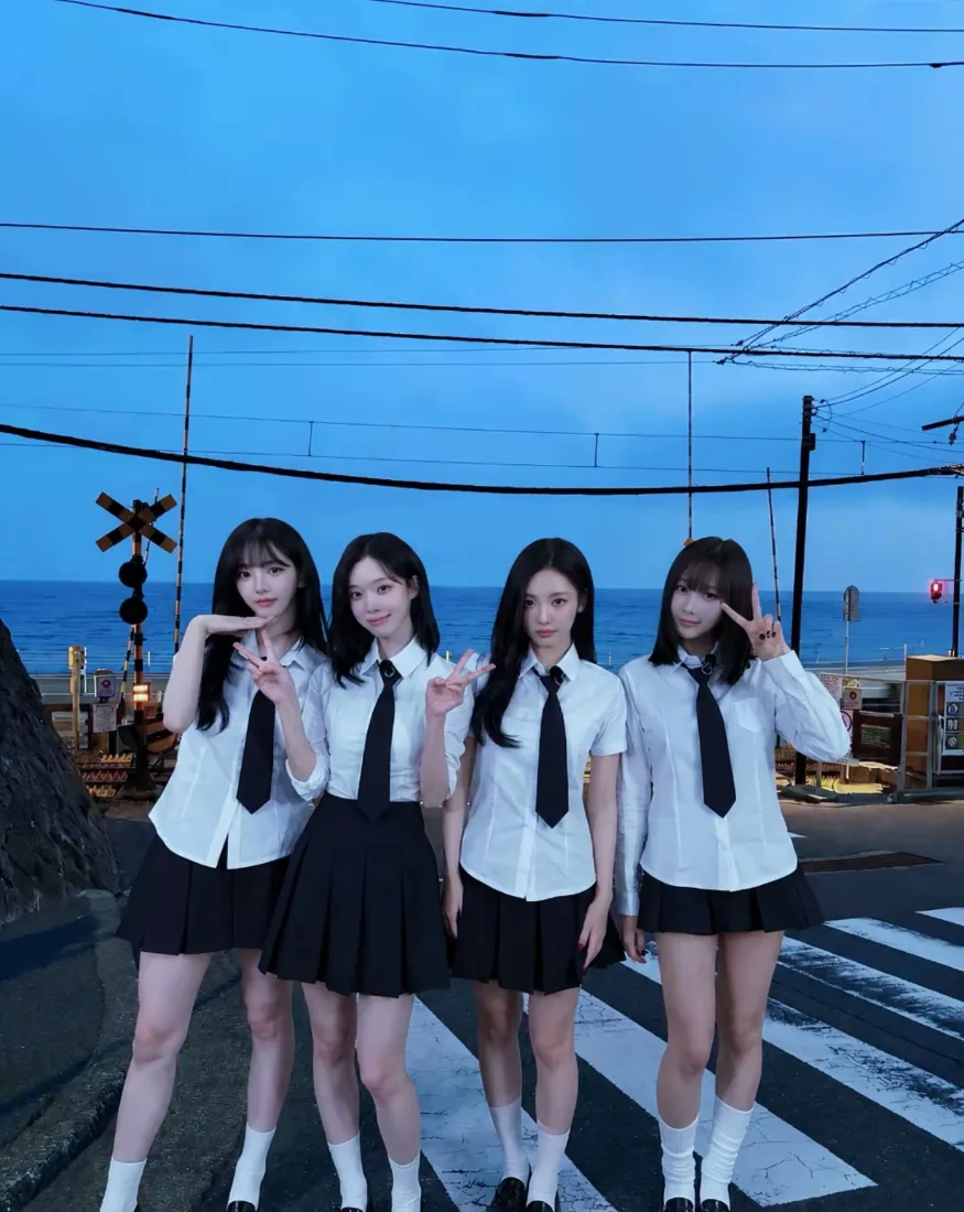 四名穿JK制服的少女站在海边铁路道口斑马线上，背景是蓝色黄昏天空与海面。
