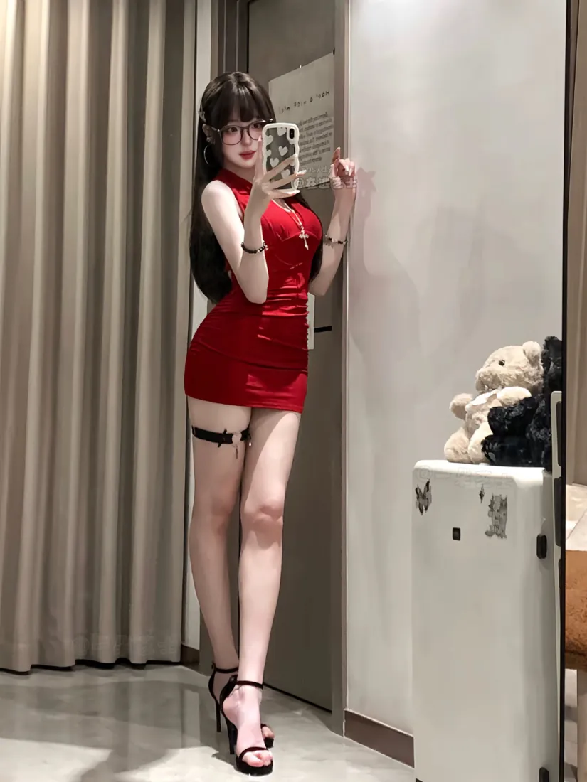 穿红色紧身短裙的戴眼镜女生在试衣间对镜自拍，搭配腿环与高跟凉鞋。